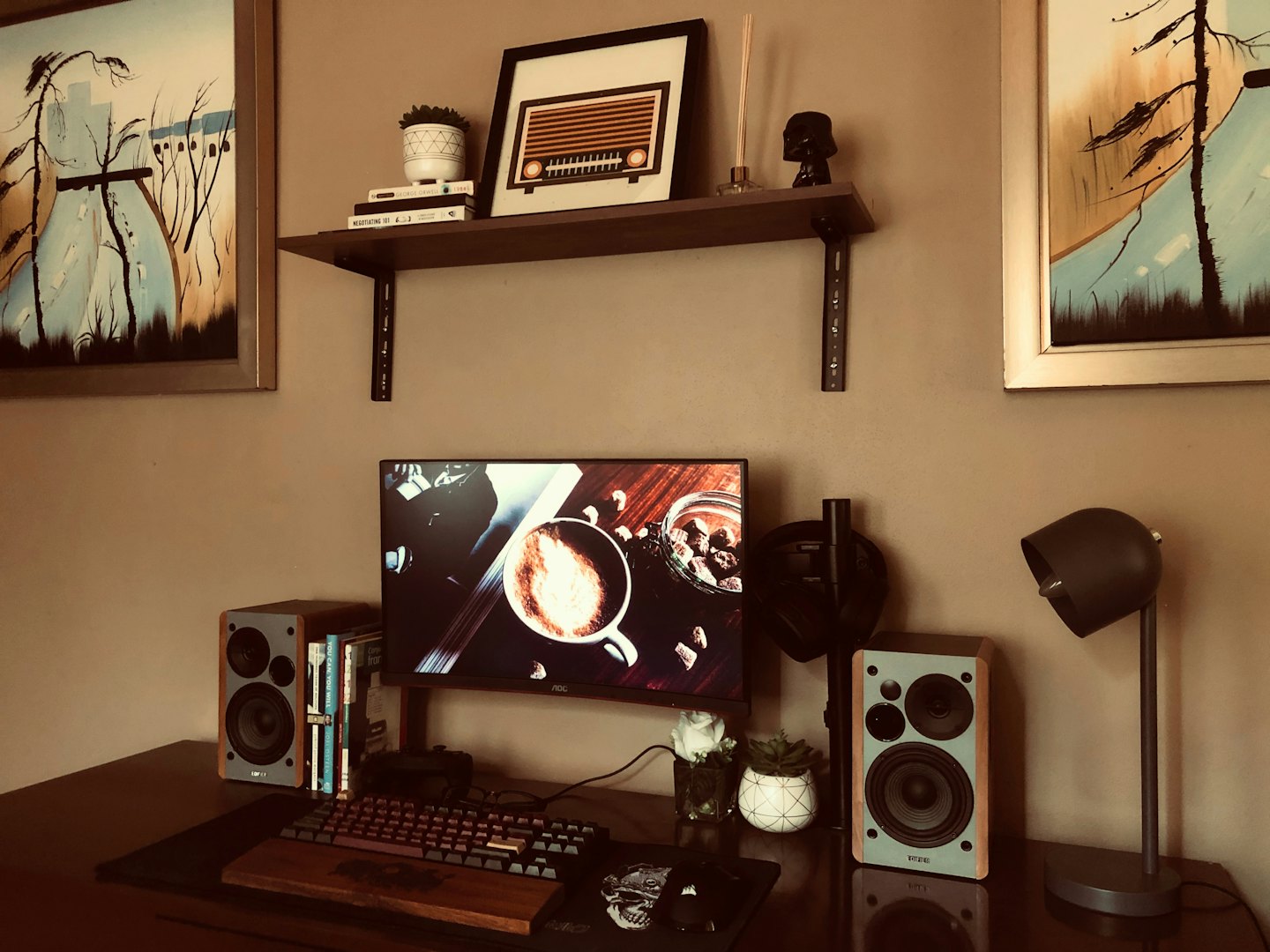 Modern home office desk with computer, keyboard, and wall art.