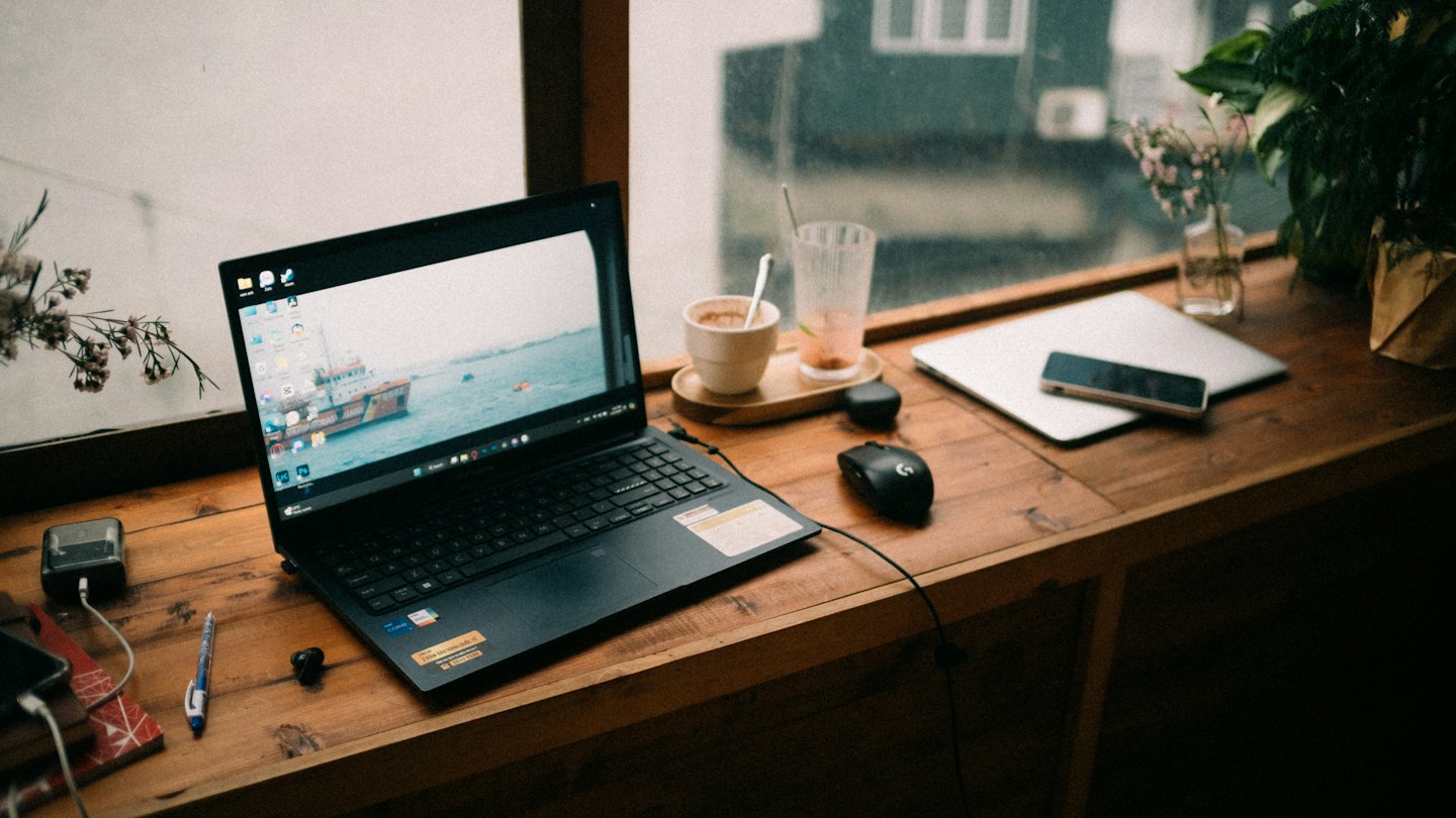 Black laptop and home office supplies on a wooden desk.