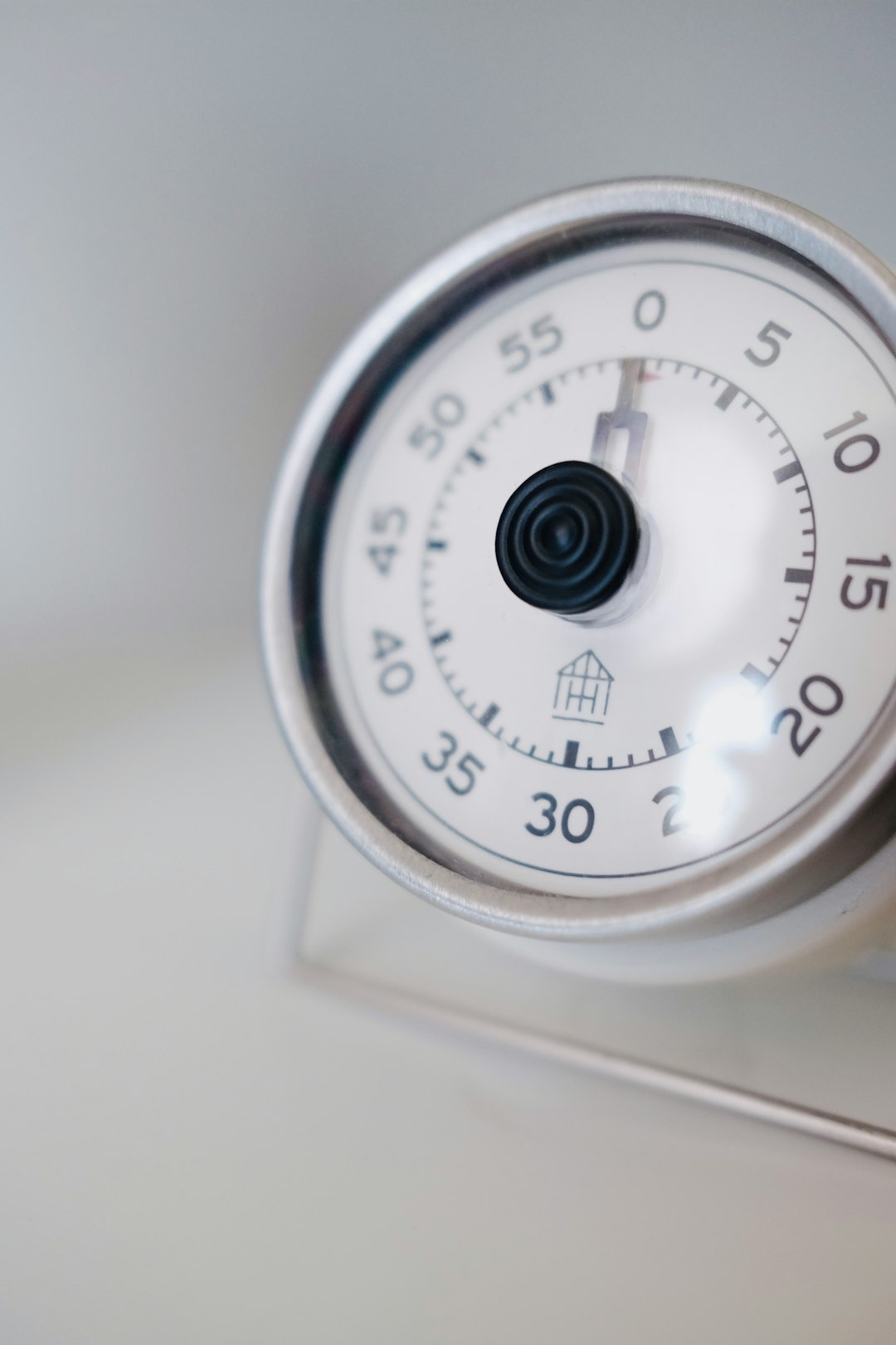 Silver kitchen timer with black numbers sitting on a table.